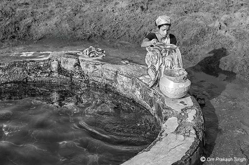 Filtering drinking water on the cemented parapet of the Paata Daarhi in Kudda village